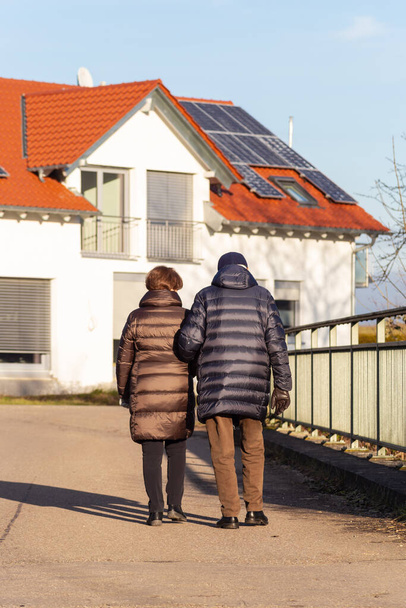pareja de ancianos caminando en la calle wiht casas de nueva construcción
 - Foto, imagen