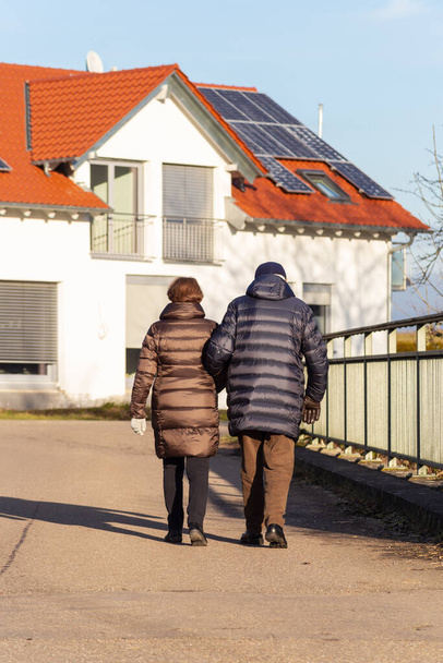 ηλικιωμένο ζευγάρι περπατά στο δρόμο με νεόδμητα σπίτια - Φωτογραφία, εικόνα