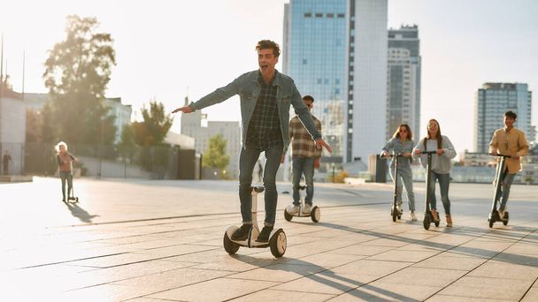 Get a vehicle, get a life. A group of friends riding kick scooters and segways on a sunny day - 写真・画像