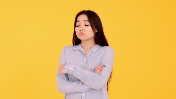offended Asian young girl on yellow background. copy space - Πλάνα, βίντεο