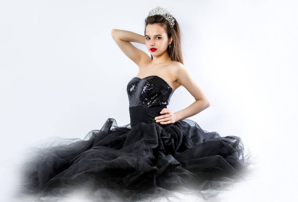 Beautiful young woman in luxurious long black dress sitting on the floor. Fashion photo. - Foto, Imagem