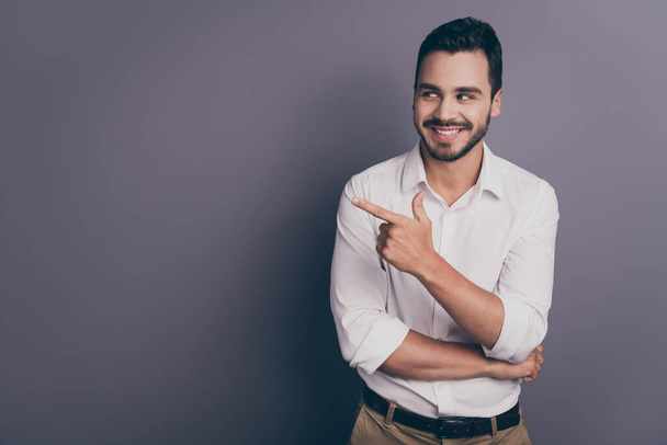 Photo of handsome business man friendly smiling indicating finger empty space advising novelty product interesting offer wear white office shirt pants isolated grey color background - Φωτογραφία, εικόνα