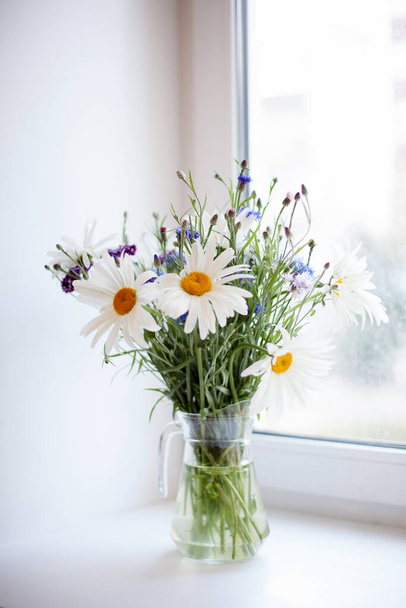 Still life with   bouquet of wild flowers in   transparent jug.  - Фото, зображення