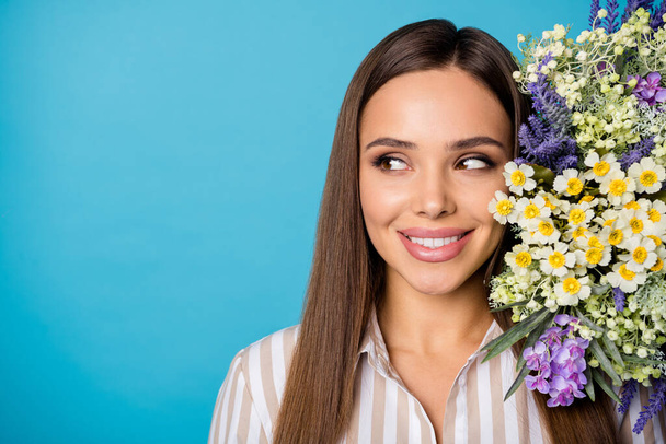 Closeup photo of charming lady enjoy wildflowers bunch present banner idea concept look side empty space see advert offer wear striped shirt isolated blue color background - Foto, imagen