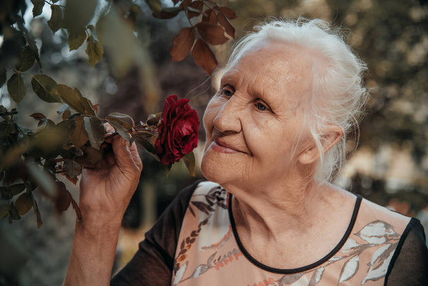 Portret van de oudere lachende vrouw met bloemen, moeder dag - Foto, afbeelding