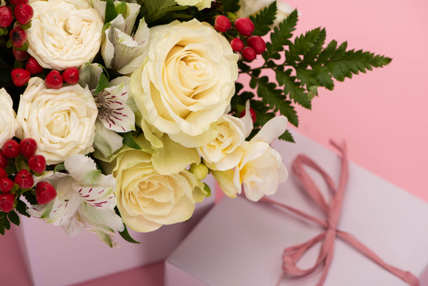 close up view of bouquet of flowers in festive gift box with bow on pink background - Photo, Image