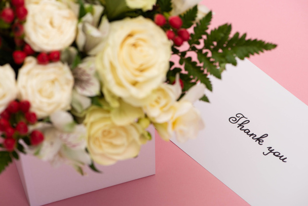 selektivní zaměření kytice květin ve slavnostní dárkové krabici v blízkosti poděkování přání na růžovém pozadí - Fotografie, Obrázek