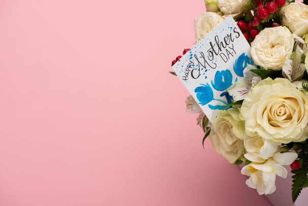 bouquet of flowers in festive gift box with mothers day greeting card on pink background - Foto, immagini