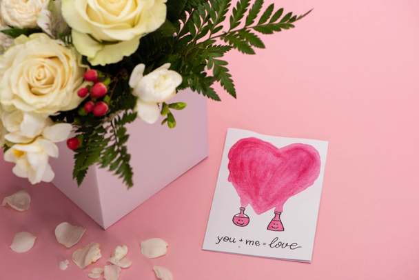 букет цветов в праздничной подарочной коробке с поздравительной открыткой на розовом фоне
 - Фото, изображение