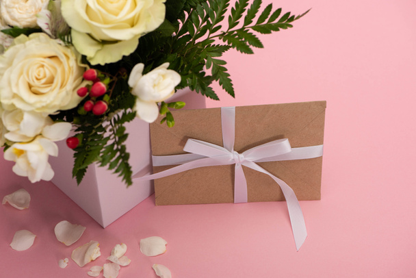 bouquet de fleurs en coffret cadeau festif avec carte de voeux et pétales sur fond rose
 - Photo, image