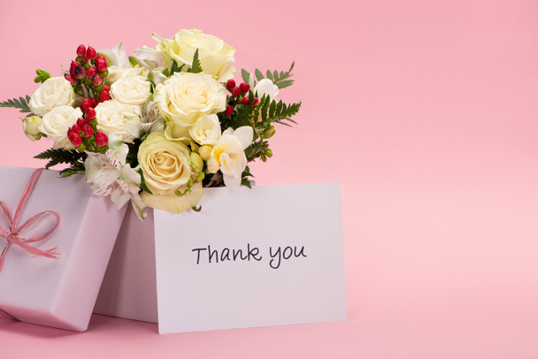 bouquet de fleurs dans une boîte cadeau festive avec arc près de carte de remerciement sur fond rose
 - Photo, image
