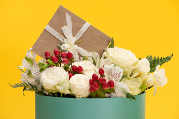spring fresh bouquet of flowers in festive gift box with greeting card isolated on yellow - Photo, Image