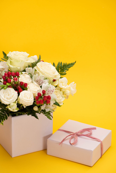 spring fresh bouquet of flowers in festive gift box on yellow background - 写真・画像