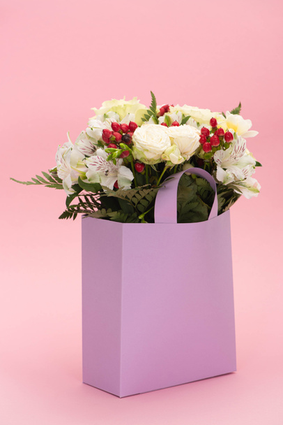 bouquet of flowers in violet paper bag on pink background - Φωτογραφία, εικόνα
