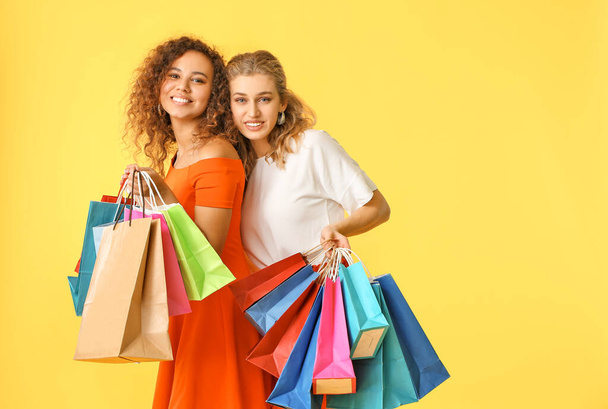Güzel genç kadınlarla renk arka plan üzerinde alışveriş torbaları - Fotoğraf, Görsel