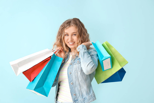 Beautiful young woman with shopping bags on color background - Photo, image