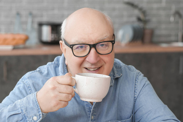 Portrait of elderly man drinking tea in kitchen - Фото, изображение