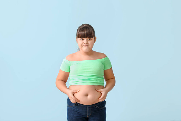 Trauriges übergewichtiges Mädchen auf farbigem Hintergrund - Foto, Bild