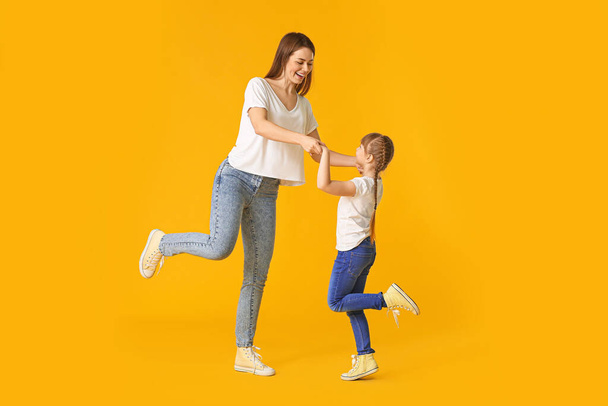 Счастливая мать и ее маленькая дочь танцуют на цветном фоне
 - Фото, изображение
