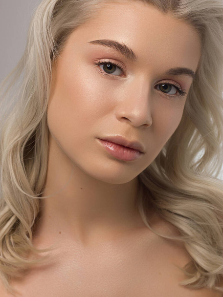 Closeup portrait of a woman with developing straight hair. Sweet tender young girl blonde. Natural lipstick, transparent clean skin. Skin care natural cosmetics in the spa salon or cosmetology. - Foto, afbeelding