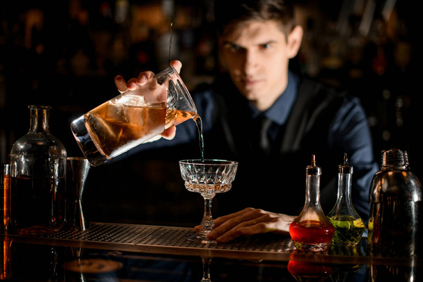bartender gently starts pouring a cocktail into a wineglass - Fotografie, Obrázek