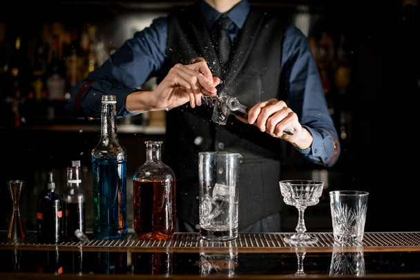 Bartender splits pieces of ice to make a cocktail. - Fotoğraf, Görsel