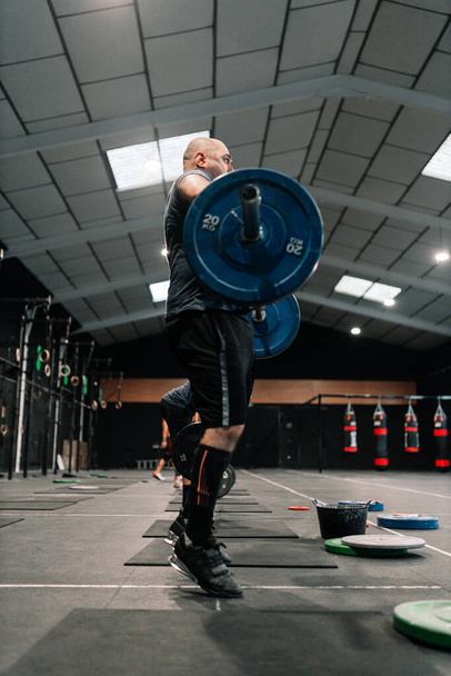 Hombre calvo adulto levantador de pesas haciendo ejercicio en el gimnasio
 - Foto, Imagen