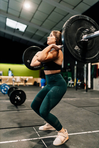 Mujer joven levantador de pesas haciendo ejercicio en el gimnasio
 - Foto, imagen