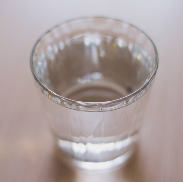 Täysi lasi vettä kevyellä puupöydällä. Valikoiva painopiste
 - Valokuva, kuva