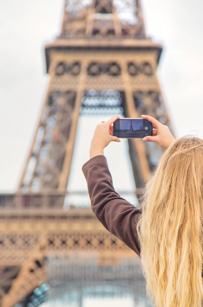 A girl photographs the Eiffel Tower in Paris on a telephone. Selective focus. nature. - Zdjęcie, obraz