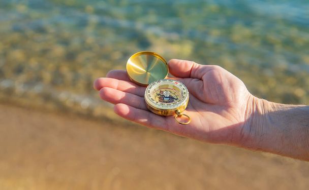 A man with a compass in his hands near the sea. Selective focus. nature. - Photo, Image
