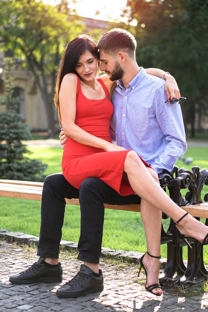 Beautiful couple of man and woman sitting on a bench in a park. Romantic theme with a girl and a guy. Spring Summer theme - Foto, Bild