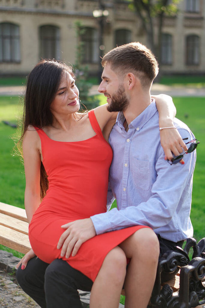Gyönyörű pár férfi és nő ül egy padon egy parkban. Romantikus téma egy lánnyal és egy sráccal. Tavaszi nyári téma - Fotó, kép