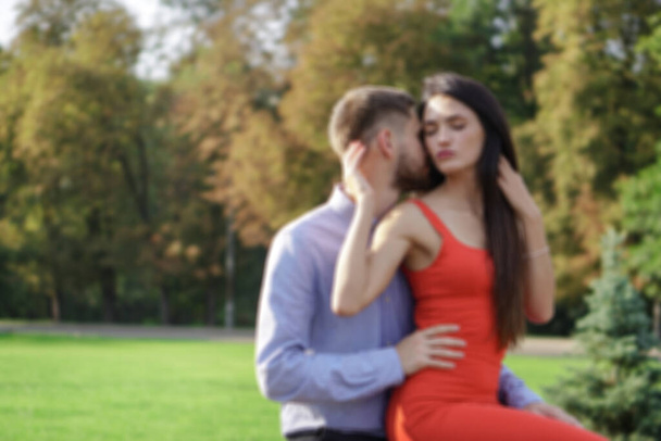 Beautiful couple of man and woman sitting on a bench defocus background. Romantic theme with a girl and a guy. Spring Summer Temma relationship, love, Valentine's day - Valokuva, kuva