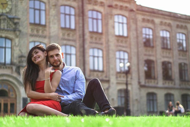 Güzel bir çift kadın ve erkek çimlerin üzerinde oturuyor. Bir kız ve bir erkekle romantik bir tema. Bahar Yaz filmi ilişkisi, aşk, Sevgililer Günü - Fotoğraf, Görsel