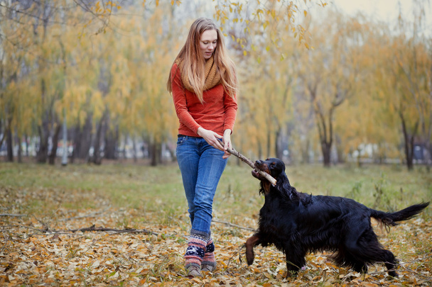 Girl and her dog playing in the autumn park - Photo, image