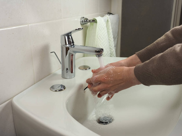Unerkennbarer Mann wäscht sich zu Hause aus Gesundheitsgründen sorgfältig die Hände - Foto, Bild
