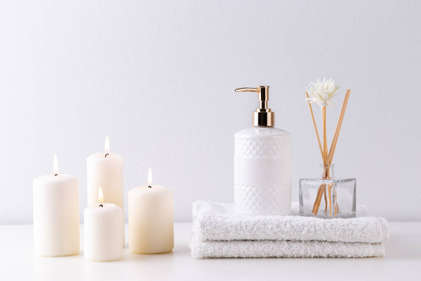 Artículos de salud y spa en estantes blancos, toallas, velas y jabón
 - Foto, Imagen
