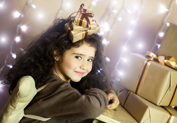 Симпатичні усміхнені маленька дівчинка, що сидить поруч з різдвяні подарунки - Фото, зображення