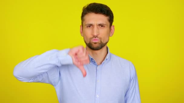 Young man in light blue shirt shows dislike, thumb down. - Video, Çekim