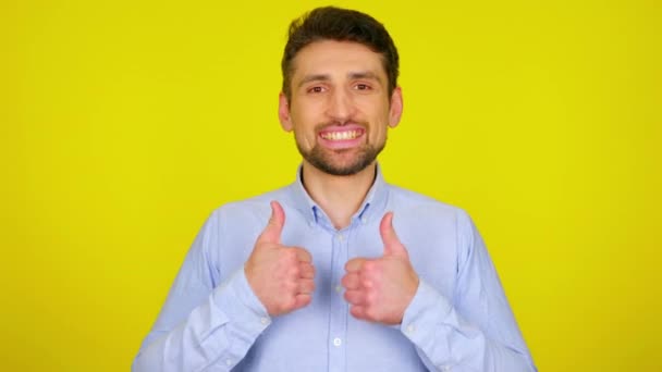 Молодий чоловік у світло-блакитній сорочці посміхається і показує великий палець, як
. - Кадри, відео