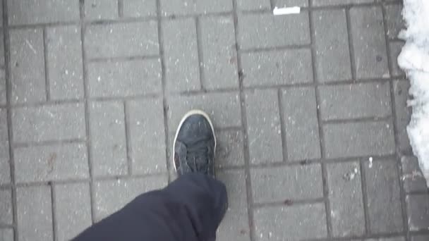 man in black sneakers walks on the sidewalk, ceramic tiles on the street - Video