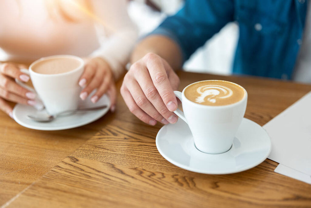 man and woman holding cups of hot coffee, closeup. - Zdjęcie, obraz