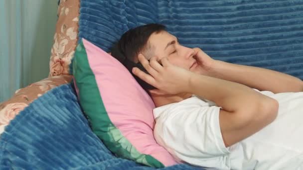 giovane uomo millenario con le cuffie in testa sdraiato sul divano ascolta musica calma e rilassante
 - Filmati, video
