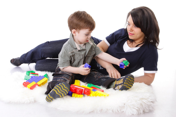 toegewijde moeder spelen met gekleurde blokken met haar nieuwsgierig zoon - Foto, afbeelding