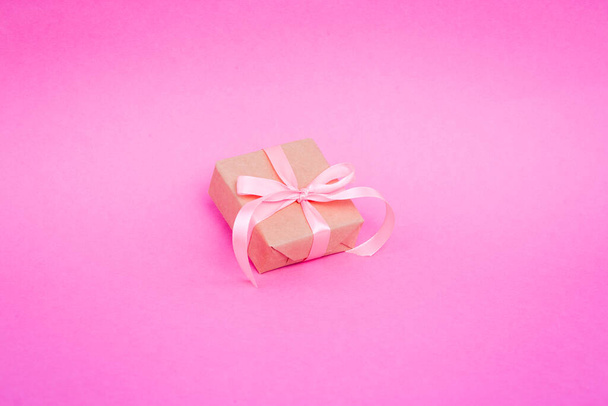 Gift wrapped in parchment, eco paper, kraft paper on a pink background. - Фото, зображення