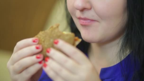 Kobieta z apetytem je hamburgera podczas lunchu. - Materiał filmowy, wideo