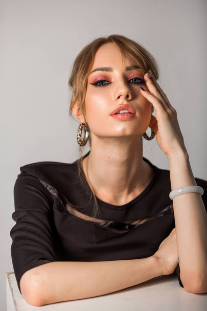 beautiful young woman with make-up in black clothes on a gray background - Φωτογραφία, εικόνα
