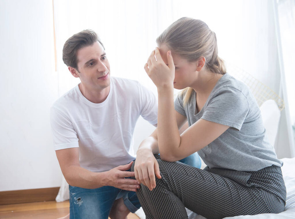 Young caucasian man comforting sad woman and sit on begin bedroom - Photo, Image