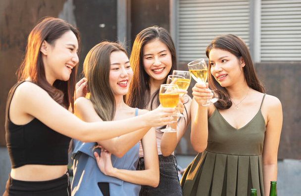 Grupa azjatyckich wielu płci gospodarstwa szklankę czatu wina wraz z przyjaciółmi podczas świętowania imprezy tanecznej na zewnątrz dachu klubu nocnego, rekreacyjny styl życia młodych przyjaźni koncepcji przyjemności. - Zdjęcie, obraz